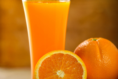 Orange juice glass and fresh oranges on wood