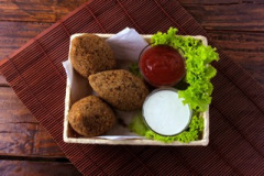 Fried kibbeh with tomato sauce in a basket, over rustic wooden table
